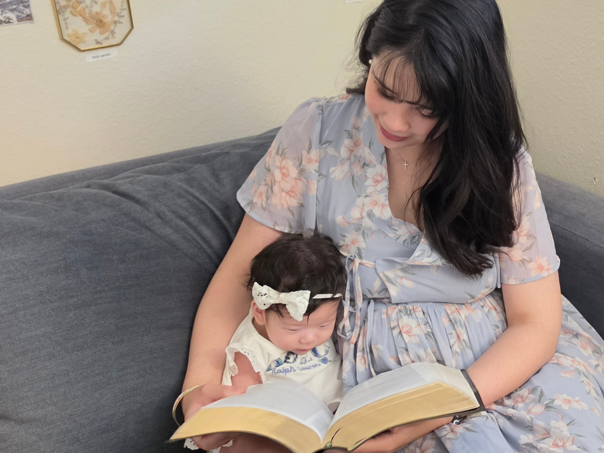 Image of Anne with her baby reading the bible>